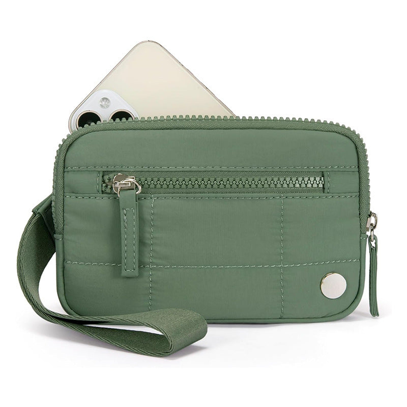 Green waterproof quilted handbag with wrist strap and front zipper, ideal for storing tech gadgets in a stylish urban design.